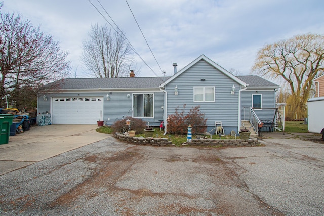 ranch-style house with entry steps, a garage, driveway, and a chimney