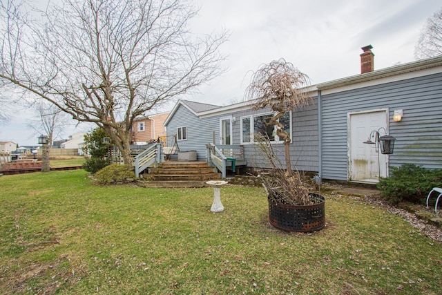 back of house with a yard, a wooden deck, and a chimney