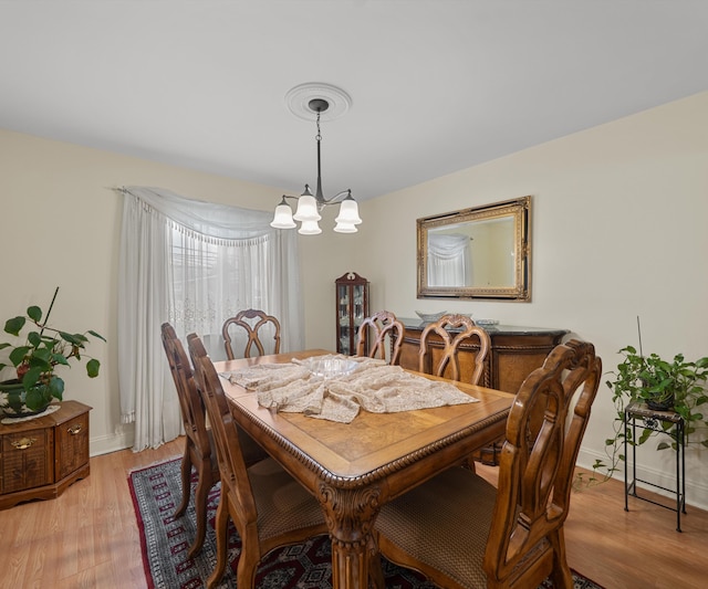 dining room with light wood finished floors, baseboards, and an inviting chandelier