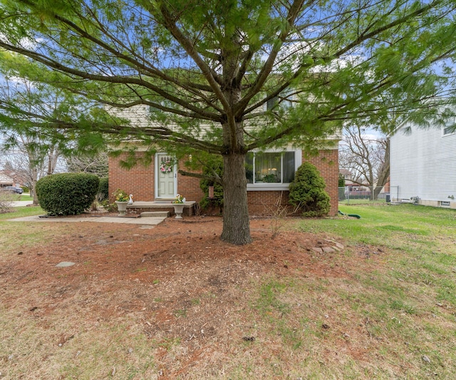view of property hidden behind natural elements featuring a front lawn and brick siding