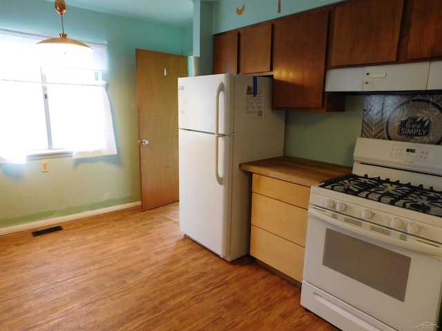 103 W Ludington Dr, Farwell, MI 48622 - kitchen featuring white appliances, under cabinet range hood, light wood-style floors, dark countertops, and decorative light fixtures
