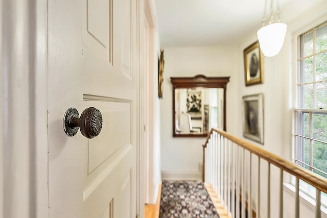 hallway with baseboards and an upstairs landing