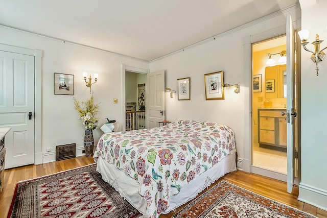 bedroom featuring baseboards, crown molding, wood finished floors, and visible vents
