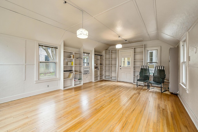 interior space featuring baseboards, vaulted ceiling, hardwood / wood-style floors, and built in shelves