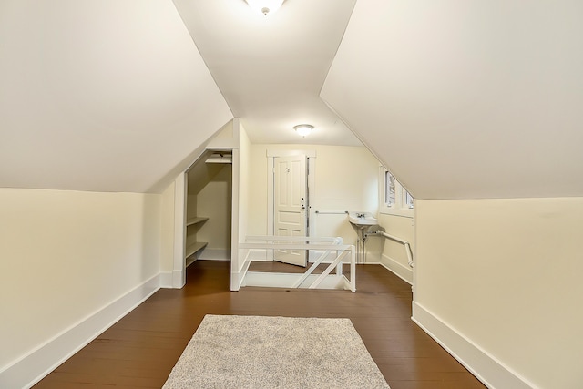 bonus room with dark wood finished floors, baseboards, and vaulted ceiling