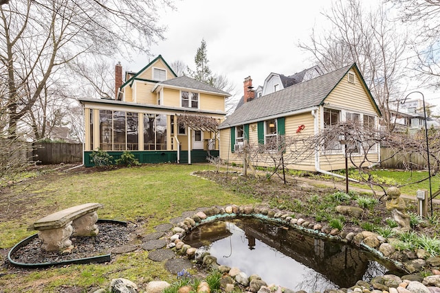 rear view of house with a chimney, a sunroom, fence, and a lawn