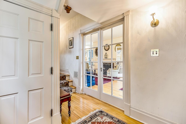 doorway featuring stairs, wallpapered walls, plenty of natural light, french doors, and light wood finished floors