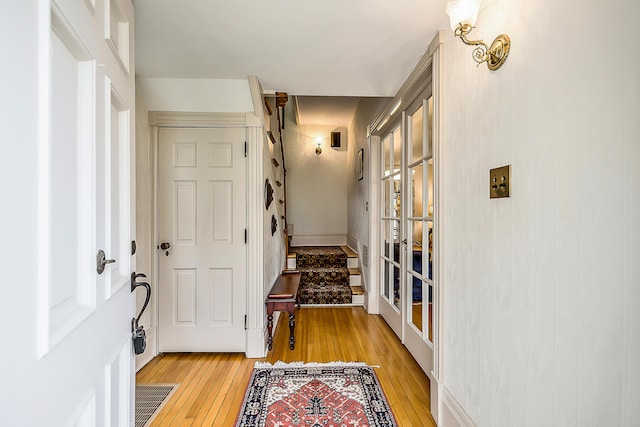 hall featuring french doors, light wood-style flooring, visible vents, and stairway
