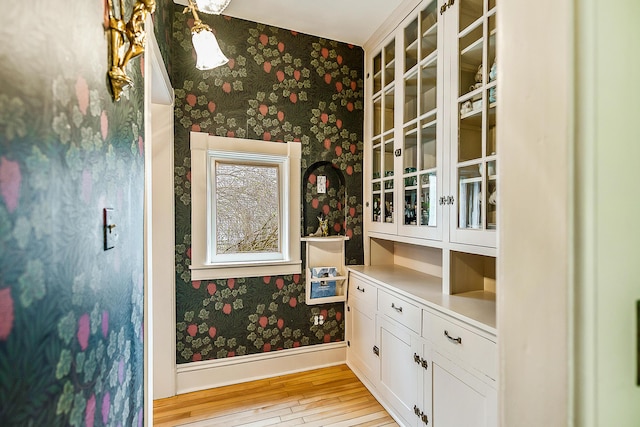 interior space with baseboards, wood finished floors, and wallpapered walls
