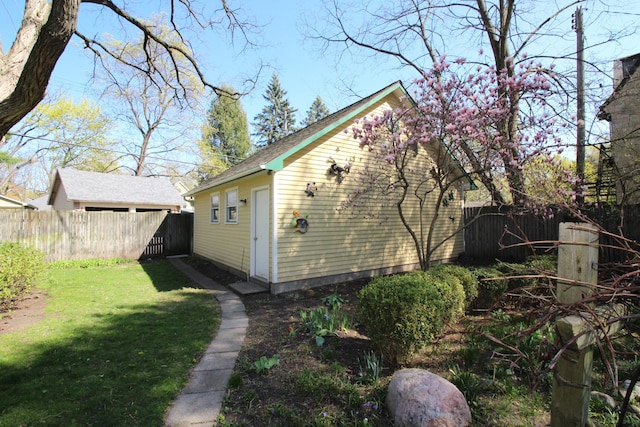view of property exterior featuring a yard, an outbuilding, and a fenced backyard