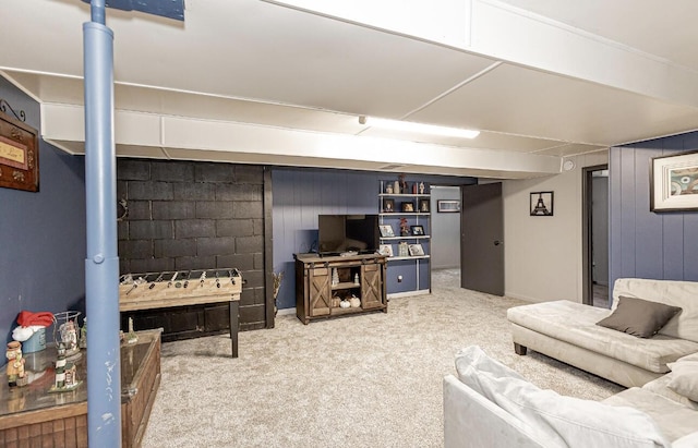 carpeted living area with concrete block wall