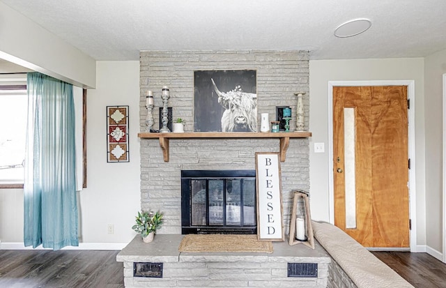living area with a textured ceiling, wood finished floors, baseboards, and visible vents