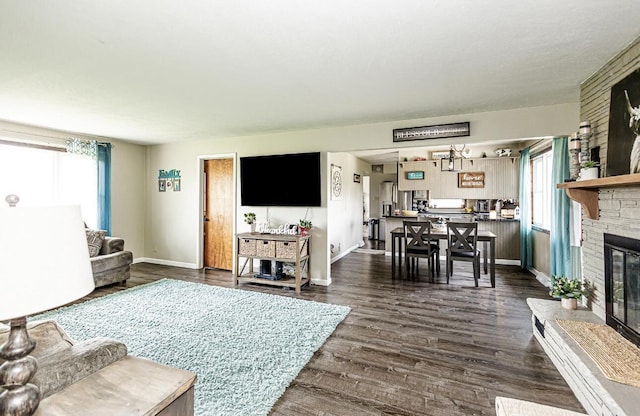 living room with baseboards, plenty of natural light, a fireplace, and dark wood-style floors