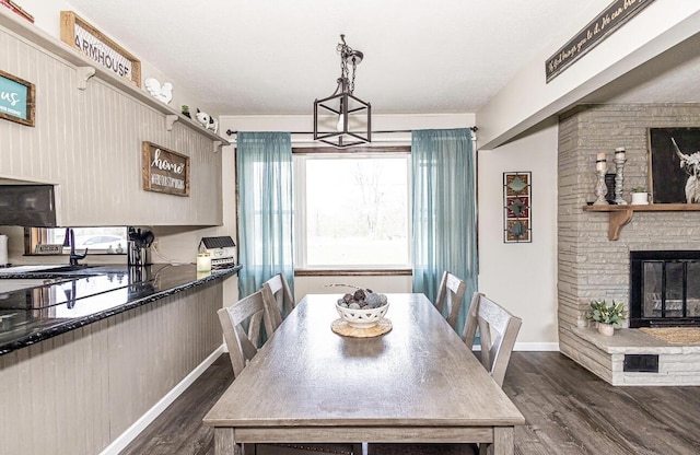 dining space featuring a fireplace, dark wood-type flooring, and baseboards