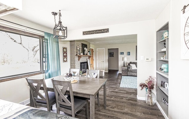 dining room featuring baseboards, dark wood-style flooring, a fireplace, and visible vents