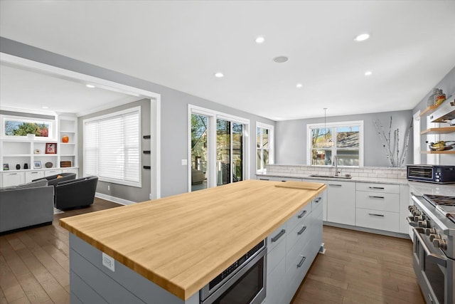 kitchen featuring appliances with stainless steel finishes, wood finished floors, a sink, a toaster, and wood counters