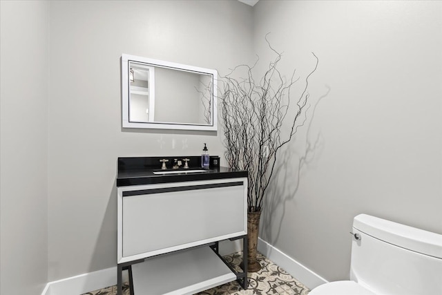 half bathroom with toilet, baseboards, and vanity