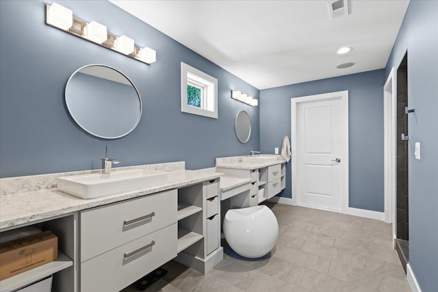 bathroom featuring visible vents, a sink, baseboards, and two vanities