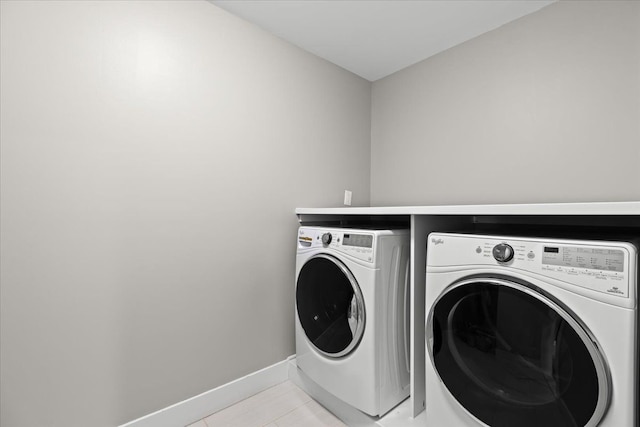 laundry area with light tile patterned flooring, laundry area, washing machine and dryer, and baseboards