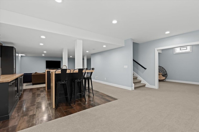dining room featuring dark carpet, stairs, recessed lighting, baseboards, and indoor bar