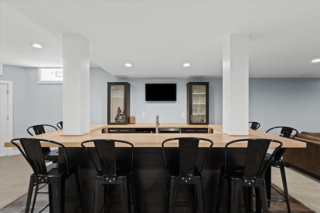 bar with indoor wet bar, recessed lighting, a sink, and carpet