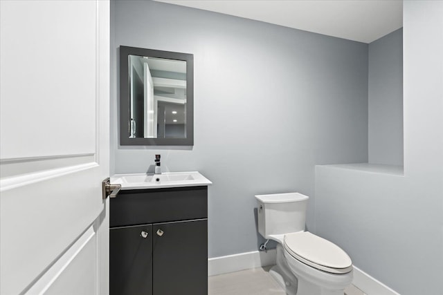 half bathroom with toilet, baseboards, and vanity