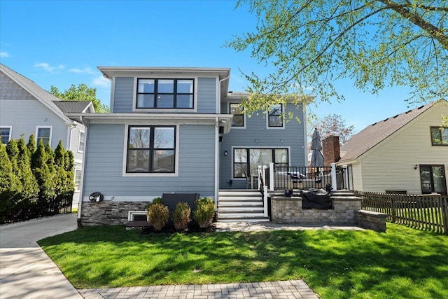 rear view of property with fence, a wooden deck, and a lawn