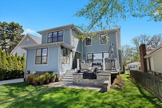 rear view of house featuring fence, a yard, and a deck