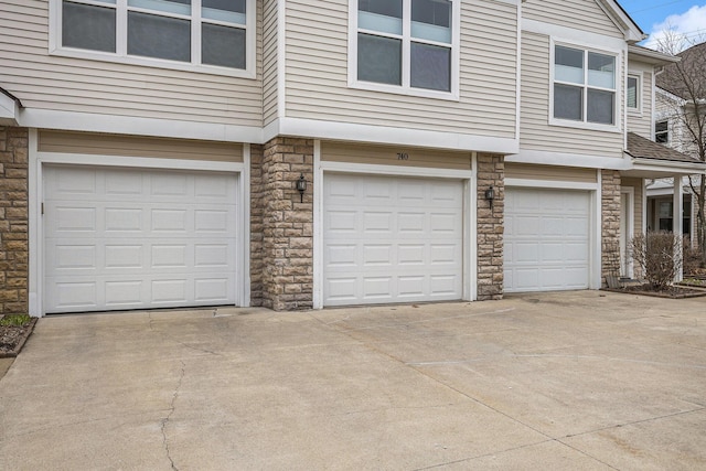 exterior space with a garage, stone siding, and concrete driveway
