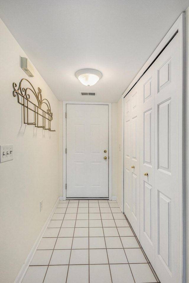 doorway to outside with light tile patterned flooring, baseboards, and visible vents