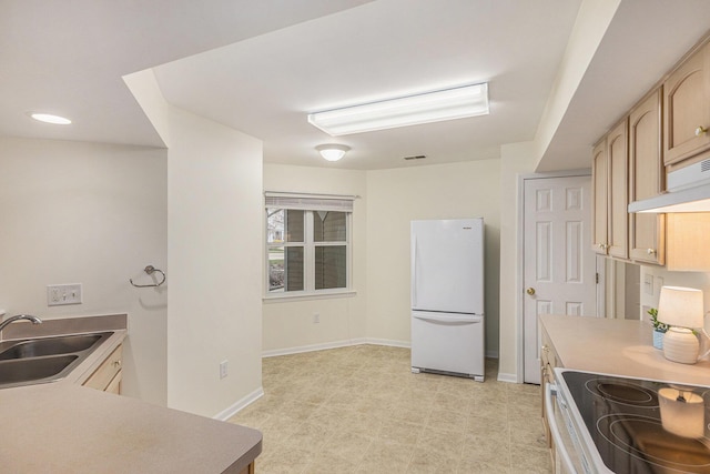 kitchen with baseboards, light brown cabinets, a sink, freestanding refrigerator, and under cabinet range hood