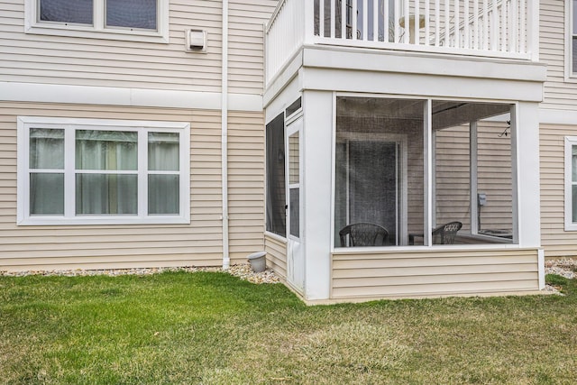 exterior space with a balcony, a sunroom, and a lawn