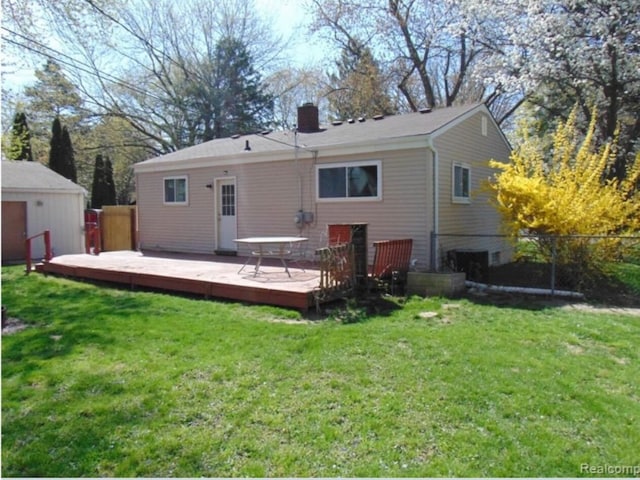 rear view of house with a yard, a wooden deck, fence, and a chimney