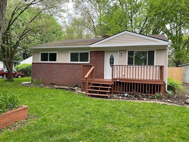 single story home with a front yard, brick siding, a deck, and fence