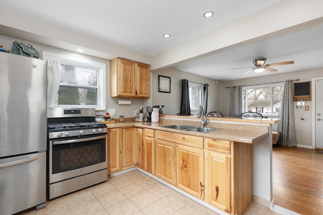 kitchen with a sink, appliances with stainless steel finishes, light brown cabinetry, a peninsula, and recessed lighting