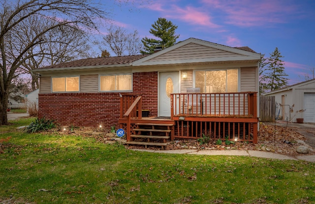 back of property at dusk featuring a yard, a wooden deck, and brick siding