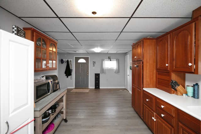 69465 High St, Union, MI 49130 - kitchen with a drop ceiling, stainless steel microwave, light countertops, glass insert cabinets, and light wood finished floors