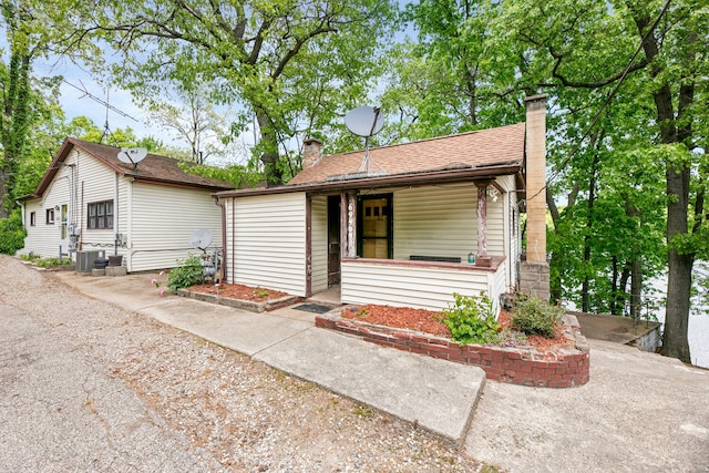 69465 High St, Union, MI 49130 - view of front of house with covered porch, a chimney, central AC, and roof with shingles