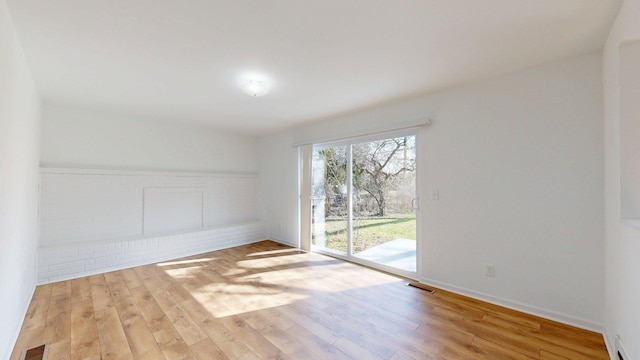 unfurnished room with wood finished floors, baseboards, and visible vents