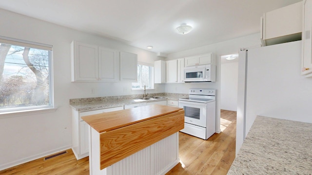 kitchen featuring white appliances, light wood-type flooring, white cabinetry, visible vents, and a sink