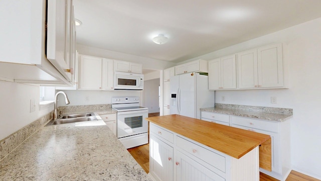 kitchen featuring a sink, white cabinetry, white appliances, and a kitchen island
