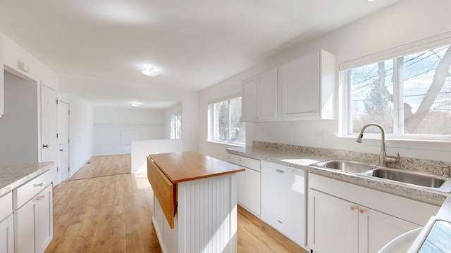 kitchen featuring white cabinets, white dishwasher, light wood-type flooring, and a sink