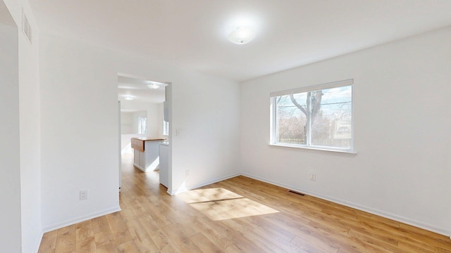spare room with light wood-style flooring, baseboards, and visible vents