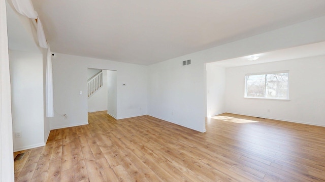 empty room with stairs, visible vents, and light wood-type flooring