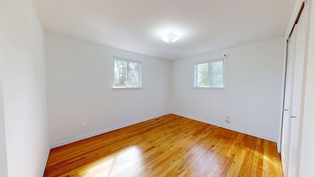 unfurnished bedroom featuring baseboards, multiple windows, and light wood-style floors
