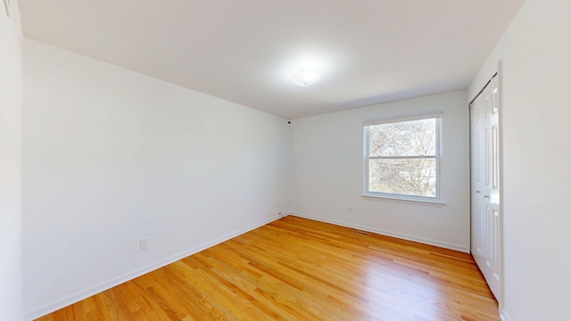 unfurnished room with baseboards and light wood-type flooring