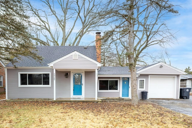 view of front of home featuring aphalt driveway, roof with shingles, a chimney, and an attached garage