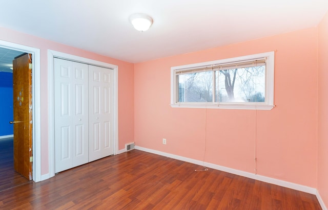 unfurnished bedroom with visible vents, a closet, baseboards, and wood finished floors