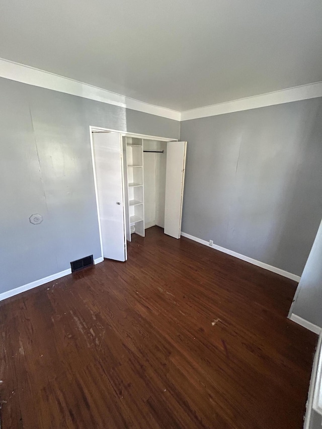 509 Mccourtie St, Kalamazoo, MI 49008 - unfurnished bedroom featuring a closet, baseboards, ornamental molding, dark wood-style floors, and visible vents