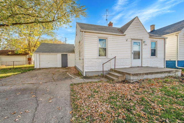 bungalow with a chimney, aphalt driveway, fence, an outdoor structure, and a garage